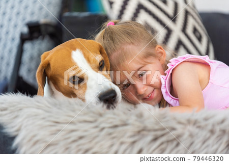 Child cuddle a dog on backyard sofa. Child cuddle a dog on backyard sofa. 79446320