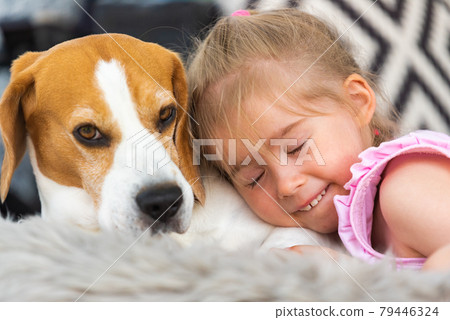 Child cuddle a dog on backyard sofa. Child cuddle a dog on backyard sofa. 79446324