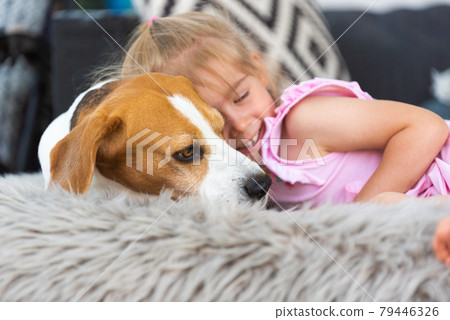 Child cuddle a dog on backyard sofa. Child cuddle a dog on backyard sofa. 79446326