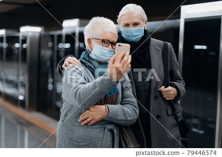 two female tourists talking on a video link in the subway. 79446574