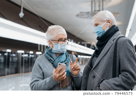 two mature women discussing something while standing on a subway platform. two mature women discussing something while standing on a subway platform. 79446575