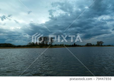 Restless evening clouds over a calm lake Restless evening clouds over a calm lake 79447850
