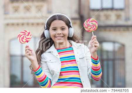 Her favorite sweet. girl in headphones. little girl in wireless headset with lollipop. Her favorite sweet. girl in headphones. little girl in wireless headset with lollipop. 79448705