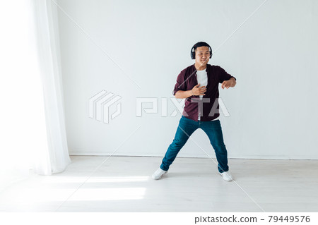 Beautiful Asian man dances to music in headphones Beautiful Asian man dances to music in headphones 79449576