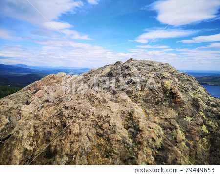 A large stone on the background of mountains with trees A large stone on the background of mountains with trees 79449653