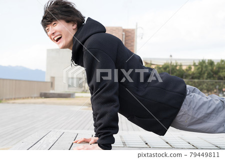 A man doing push-ups outdoors 79449811