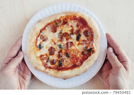 A close-up of a mini pizza in a disposable dish. Top view of takeaway food in fast food cafe. The photo shows mozzarella cheese, tomatoes, olives and various sausages. Meal for one person A close-up of a mini pizza in a disposable dish. Top view of takeaway food in fast food cafe. The photo shows mozzarella cheese, tomatoes, olives and various sausages. Meal for one person 79450481