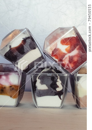 Close-up of multi-colored layered ice cream. Creative food. Vegetarian sweets. Dessert in a glass in a restaurant or cafe. Soy milk, chocolate and fruits in a beautiful dish 79450555