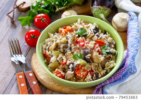 Vegetarian menu, healthy diet food. Rice with vegetables, mushrooms and eggplants in a bowl on a wooden table. Vegetarian menu, healthy diet food. Rice with vegetables, mushrooms and eggplants in a bowl on a wooden table. 79451663