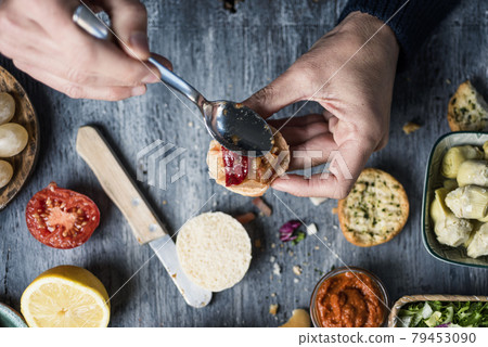 man puts some spanish escalivada on a bread bun 79453090