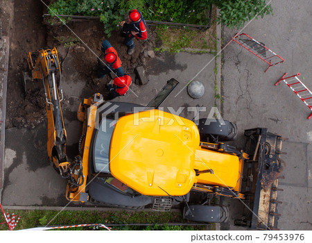 Construction site worker wearing blue overalls and red high visibility safety jacket standing Construction site worker wearing blue overalls and red high visibility safety jacket standing 79453976