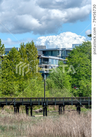 Eco cityscape. Wooden pier in front of residential building on clouds background 79456730