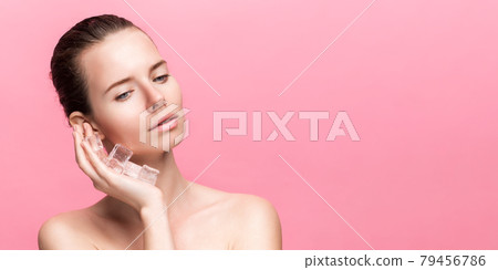 Beautiful woman with natural looking makeup holding ice cubes near face Beautiful woman with natural looking makeup holding ice cubes near face 79456786