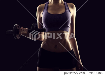 Slim athletic woman Holding dumbbell in the hand Slim athletic woman Holding dumbbell in the hand 79457486