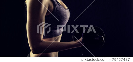 Slim athletic woman Holding dumbbell in the hand Slim athletic woman Holding dumbbell in the hand 79457487