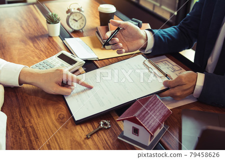 Home agents are explain to customers signing a contract to buy a new home. Home agents are explain to customers signing a contract to buy a new home. 79458626