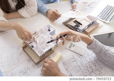 Owner and designer having a meeting while looking at a model of a house 79459723