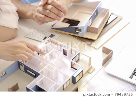 Owner and designer having a meeting while looking at a model of a house 79459736