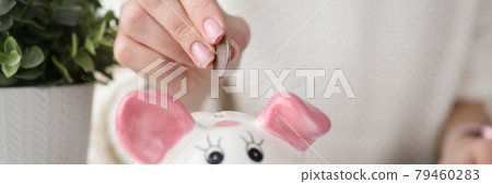 Womans hand throwing coins into piggy bank at home 79460283