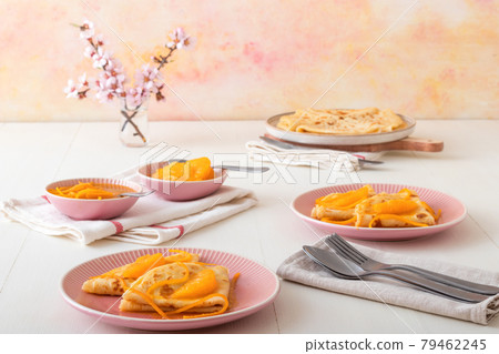 Pancakes Suzette, French traditional desert. Pancakes with oranges. White wooden table with blue fabric. Pancakes Suzette, French traditional desert. Pancakes with oranges. White wooden table with blue fabric. 79462245