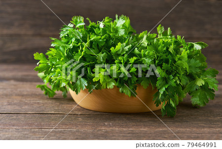 fresh parsley in a wooden bowl on the table, selective focus, rustic style. 79464991