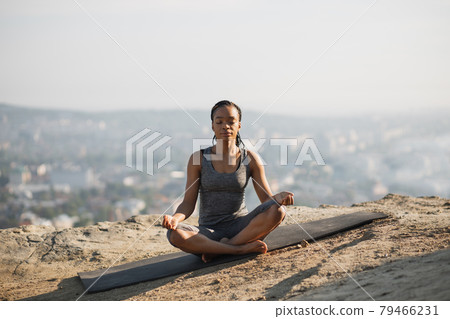 African american woman meditating on yoga mat outdoors 79466231