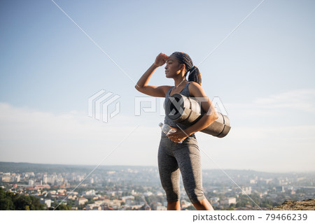 Fitness black woman holding yoga mat and water bottle 79466239