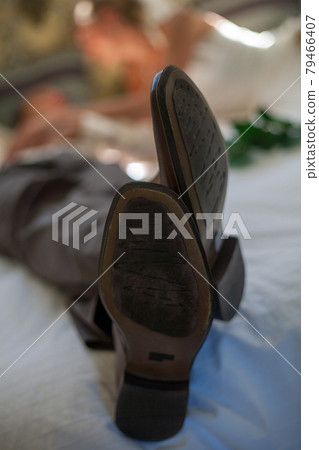 Bride and groom lying on a bed. Men's shoes closeup Bride and groom lying on a bed. Men's shoes closeup 79466407