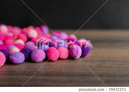 Colorful pom pom on dark wood background Colorful pom pom on dark wood background 79472371