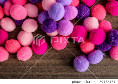 Round pink and purple fluffy balls pompoms on wooden background Round pink and purple fluffy balls pompoms on wooden background 79472373
