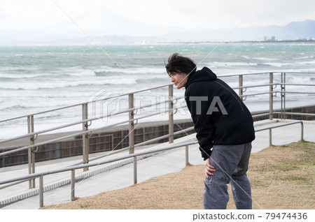 一個男人一邊看海一邊做伸展運動 79474436