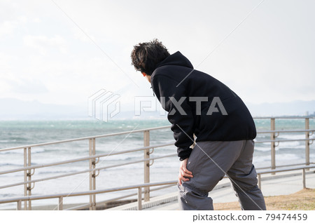 A man doing stretching exercises while looking at the sea A man doing stretching exercises while looking at the sea 79474459