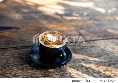 Black cup of cappuccino with latte art on saucer on wooden background Black cup of cappuccino with latte art on saucer on wooden background 79481892