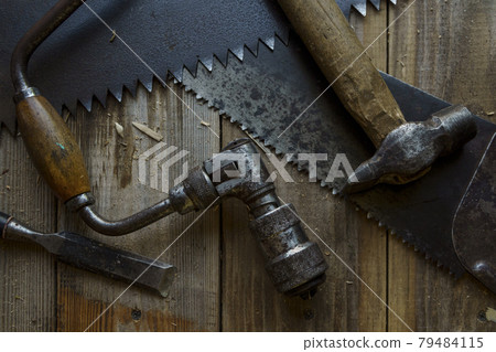 Vintage tools are hacksaw, chisel, hammer and drill on workbench in workshop Vintage tools are hacksaw, chisel, hammer and drill on workbench in workshop 79484115