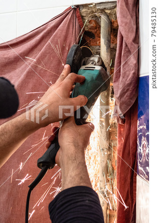 plumber cutting water pipe in wall by disc grinder 79485130