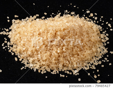 pile of demerara brown sugar closeup on black 79485427