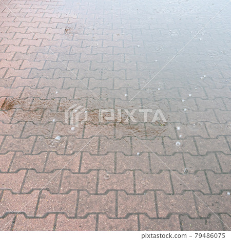 rainy puddle on stone tiles of pavement in rain 79486075