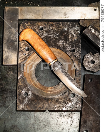 forged knife on workbench in warm light 79486077