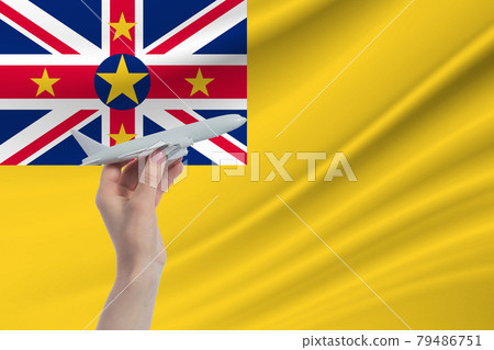 Airplane in hand with national flag of Niue. Travel to Niue Airplane in hand with national flag of Niue. Travel to Niue 79486751