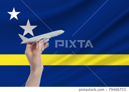 Airplane in hand with national flag of Curacao. Travel to Curacao 79486753