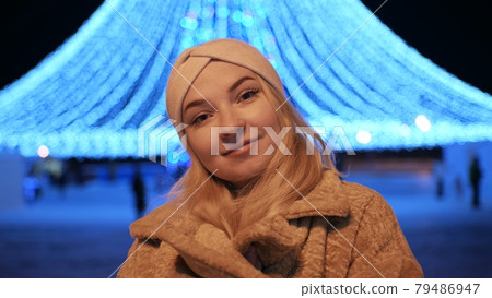 Girl posing against the backdrop of urban Christmas illumination. 79486947
