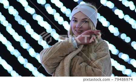 Girl posing against the backdrop of urban Christmas illumination. 79486974