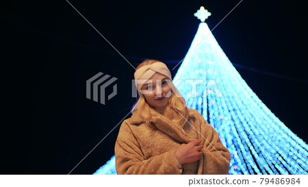 Girl posing against the backdrop of urban Christmas illumination. 79486984