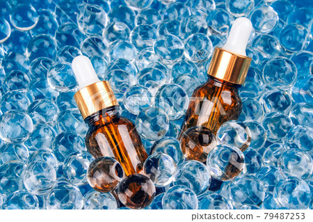Mockup image of two dropper bottles with natural organic herbal cosmetic oil on blue background of water gel balls. Trendy still life composition with copy space. Modern organic apothecary concept Mockup image of two dropper bottles with natural organic herbal cosmetic oil on blue background of water gel balls. Trendy still life composition with copy space. Modern organic apothecary concept 79487253