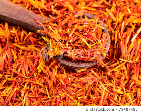spoon on pile of dried safflower petals closeup 79487483