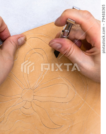 craftsman carves floral decor on leather by knife 79488365