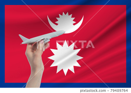 Airplane in hand with national flag of Nepal. Travel to Nepal 79489764