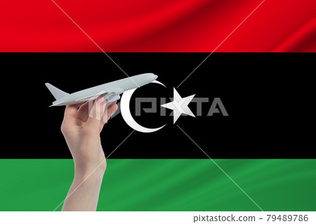 Airplane in hand with national flag of Libya. Travel to Libya 79489786