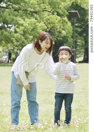 Parents and children playing soap bubbles in the park 79491365