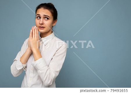 Photo of young sad worried attractive brunette woman with sincere emotions wearing white shirt Photo of young sad worried attractive brunette woman with sincere emotions wearing white shirt 79491655